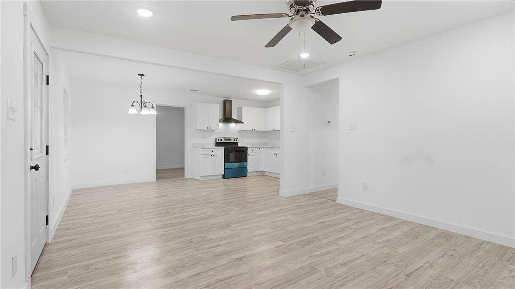 4330 Scottsdale Drive, Mesquite, TX 75150 Open floor plan featuring wood-finish flooring, white shaker cabinetry, stainless steel range with overhead hood, multi-arm chandelier, and ceiling fan with lighting
