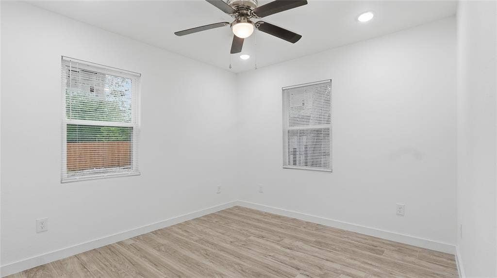 4330 Scottsdale Drive, Mesquite, TX 75150 Neutral-toned interior space featuring wood-finish flooring, two dual-pane windows, recessed ceiling lighting, and a multi-blade ceiling fan with an integrated light fixture
