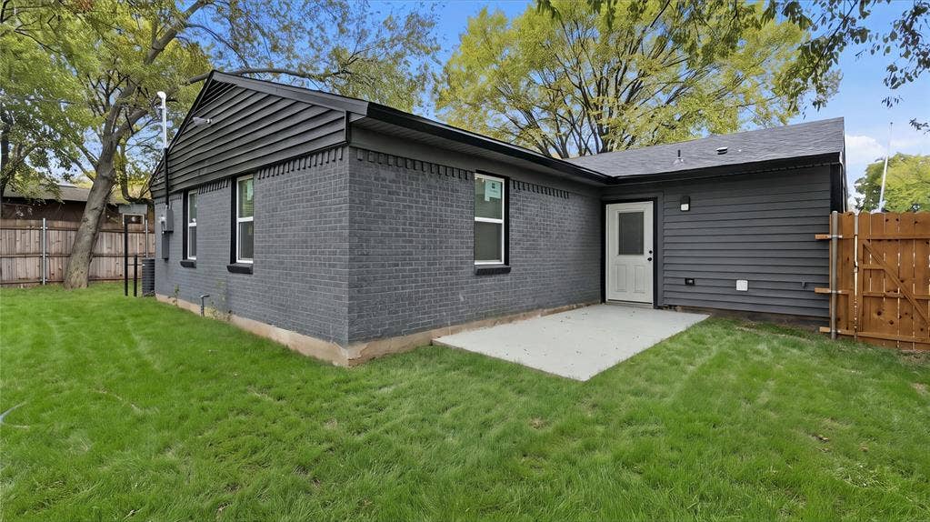 4330 Scottsdale Drive, Mesquite, TX 75150 Exterior featuring dark-toned brick and horizontal siding, a concrete patio, a rear entry door with glass insert, and wood fencing