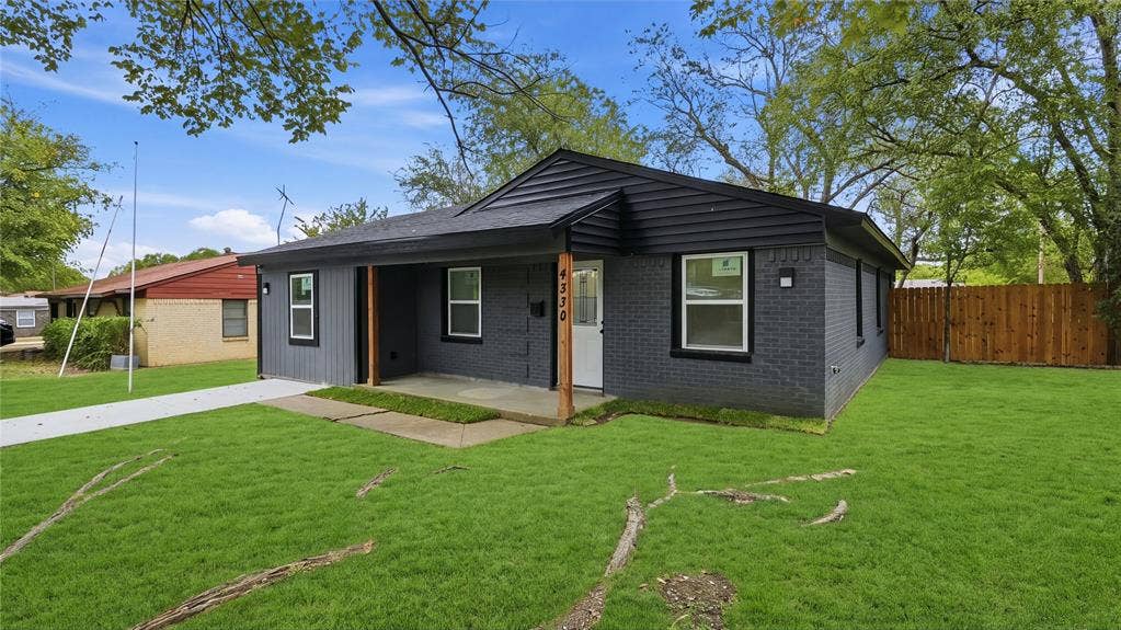 4330 Scottsdale Drive, Mesquite, TX 75150 Exterior facade featuring dark grey brick, horizontal wood siding, a covered front porch with natural wood support posts, and white window frames