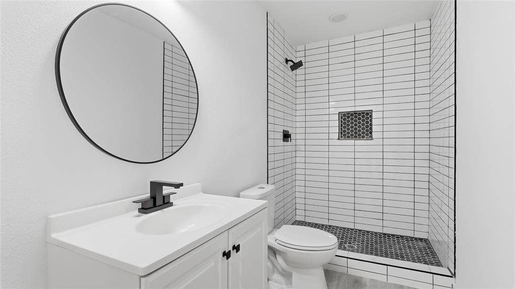 4330 Scottsdale Drive, Mesquite, TX 75150 Bathroom featuring a white vanity with a neutral countertop, round mirror, matte black plumbing fixtures, walk-in shower with white wall tile, and patterned floor tile