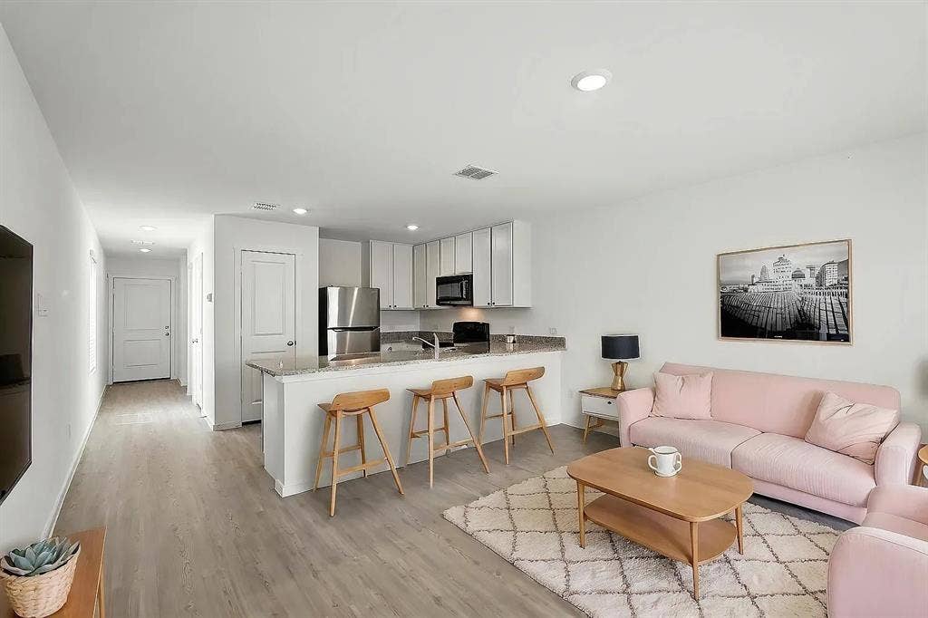 Kitchen featuring white cabinetry, stone-finish countertops, stainless steel appliances, and wood-finish flooring