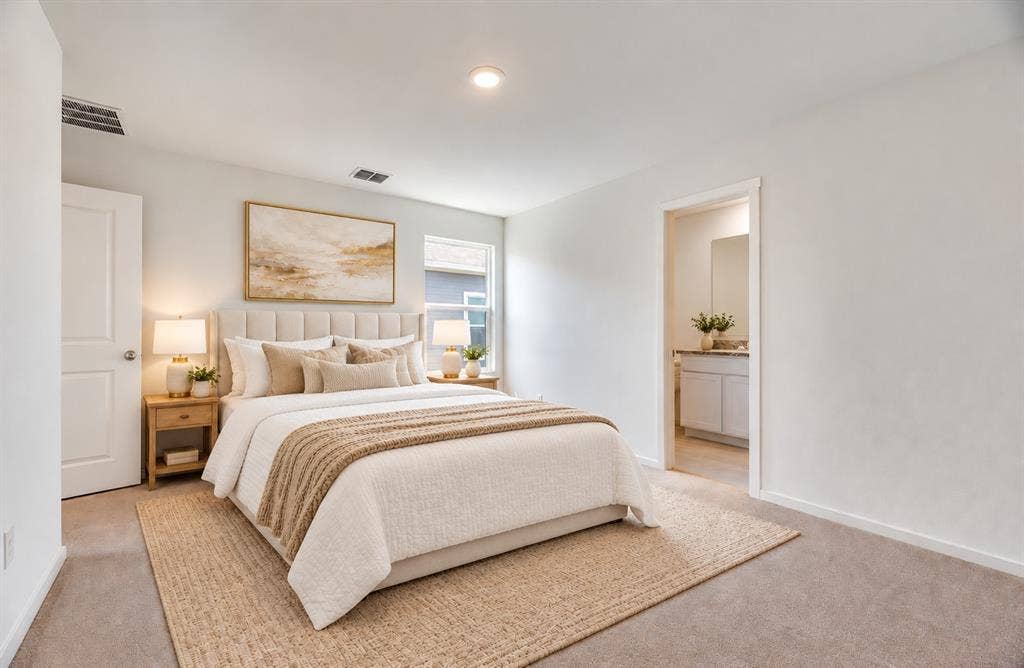 Neutral-toned interior space featuring recessed lighting, wall-to-wall carpeting, and a doorway opening to a vanity area with cabinet storage