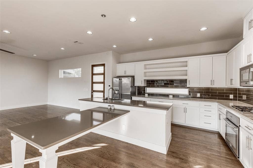 Kitchen featuring white shaker cabinetry, solid-surface countertops, extended breakfast bar, dark tiled backsplash, and wood-finish flooring