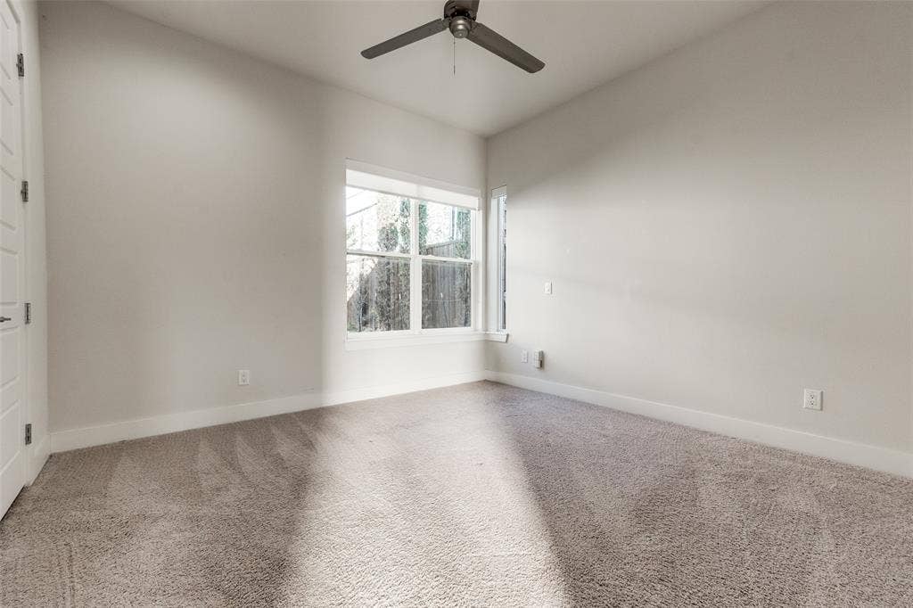 Room featuring wall-to-wall carpeting, neutral paint, multi-pane windows, and a ceiling fan with light fixture