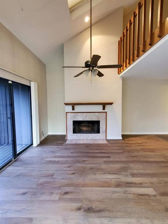 Vaulted ceilings, wood-finish flooring, stone-surround fireplace with a wood mantel, skylight, and wooden mezzanine railing