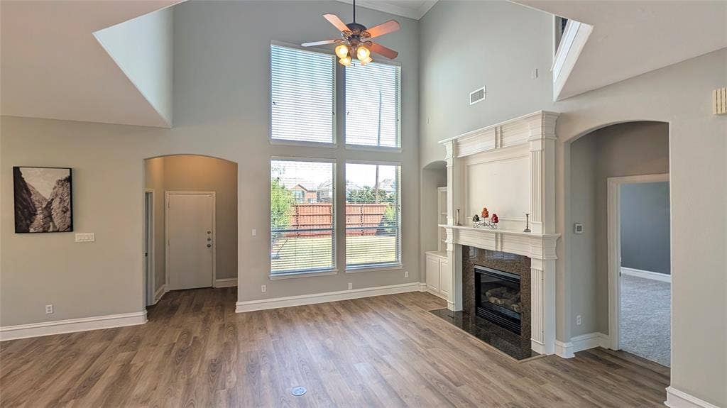 4221 Crestfield Drive, Richardson, TX 75082 Vaulted ceilings featuring a central fan, fireplace with a decorative mantel, wood-finish flooring, and expansive windows