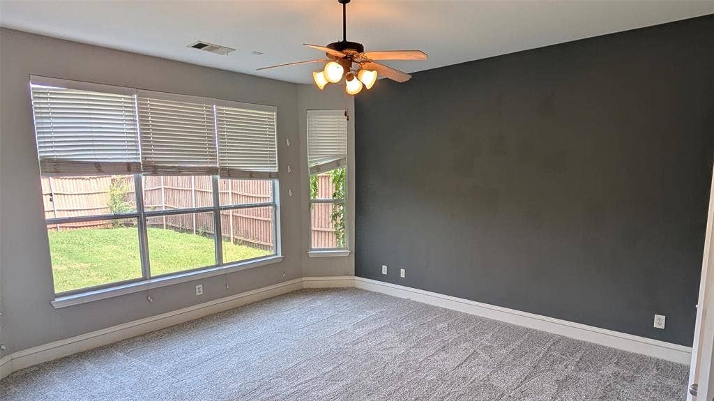 4221 Crestfield Drive, Richardson, TX 75082 Neutral-toned carpeted flooring, expansive windows with blinds, a dedicated accent wall, and a multi-bulb ceiling fan