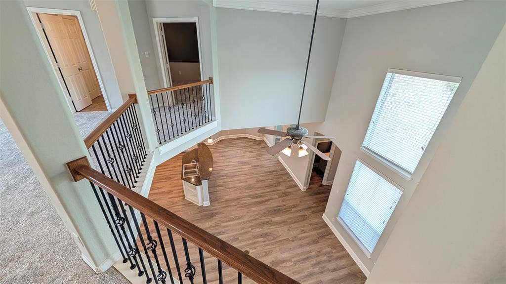 4221 Crestfield Drive, Richardson, TX 75082 Two-story foyer featuring elevated ceilings, wood-finish flooring, a wrought-iron balustrade with a stained wood handrail, and stacked windows