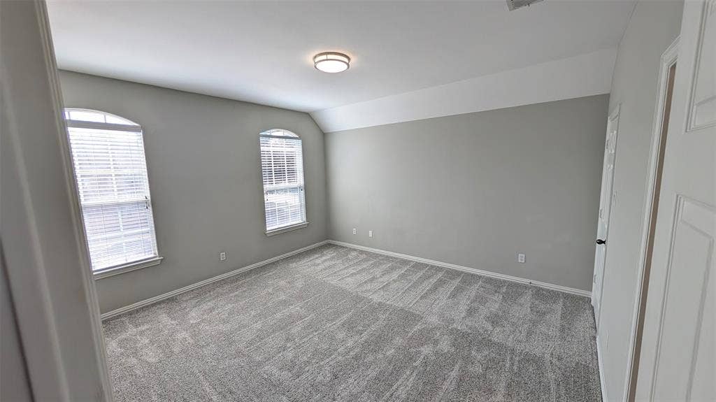 4221 Crestfield Drive, Richardson, TX 75082 Neutral-toned interior featuring plush carpeting, vaulted ceilings, and two arched windows