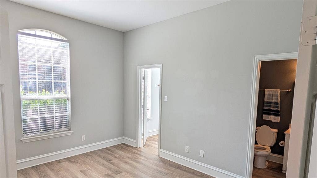 4221 Crestfield Drive, Richardson, TX 75082 Room featuring an arched window, wood-finish flooring, and neutral wall tones