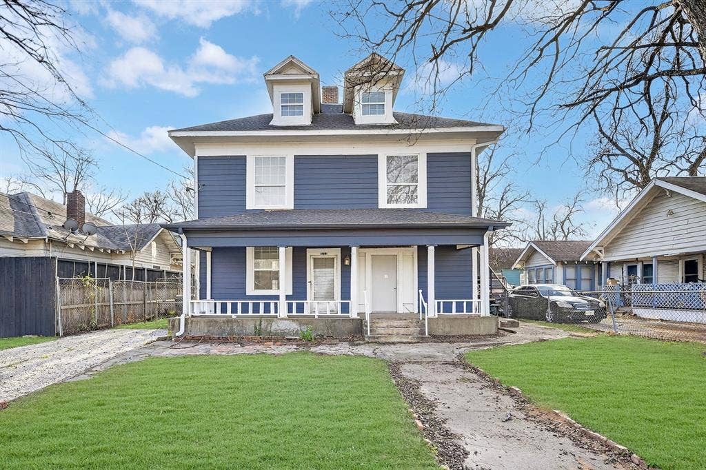 3711 Wendelkin Street, #1, Dallas, TX 75215 Two-story residence featuring blue horizontal siding, a covered front porch with white railing, and dual dormer windows