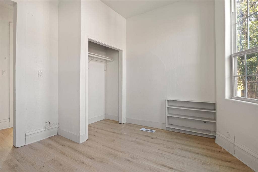 3711 Wendelkin Street, #1, Dallas, TX 75215 Interior space featuring wood-finish flooring, a built-in recessed storage shelf, a walk-in closet with integrated shelving, and a double-pane window