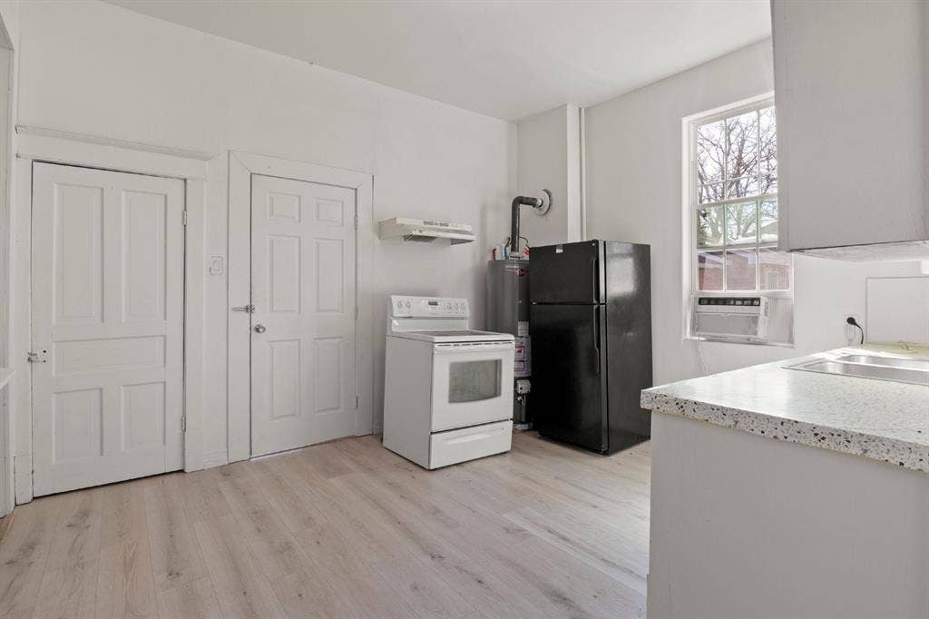 3711 Wendelkin Street, #1, Dallas, TX 75215 Kitchen area featuring wood-finish flooring, two white paneled doors, light-toned countertop, and window