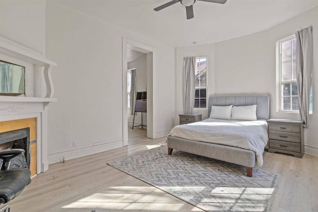 3711 Wendelkin Street, #1, Dallas, TX 75215 Decorative fireplace mantel, wood-finish flooring, bay-style window configuration, and ceiling-mounted fan