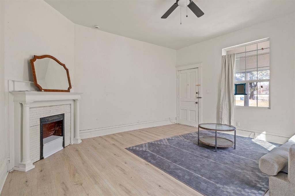 3711 Wendelkin Street, #1, Dallas, TX 75215 Living area featuring wood-finish flooring, a fireplace with a decorative mantel, and a multi-pane window