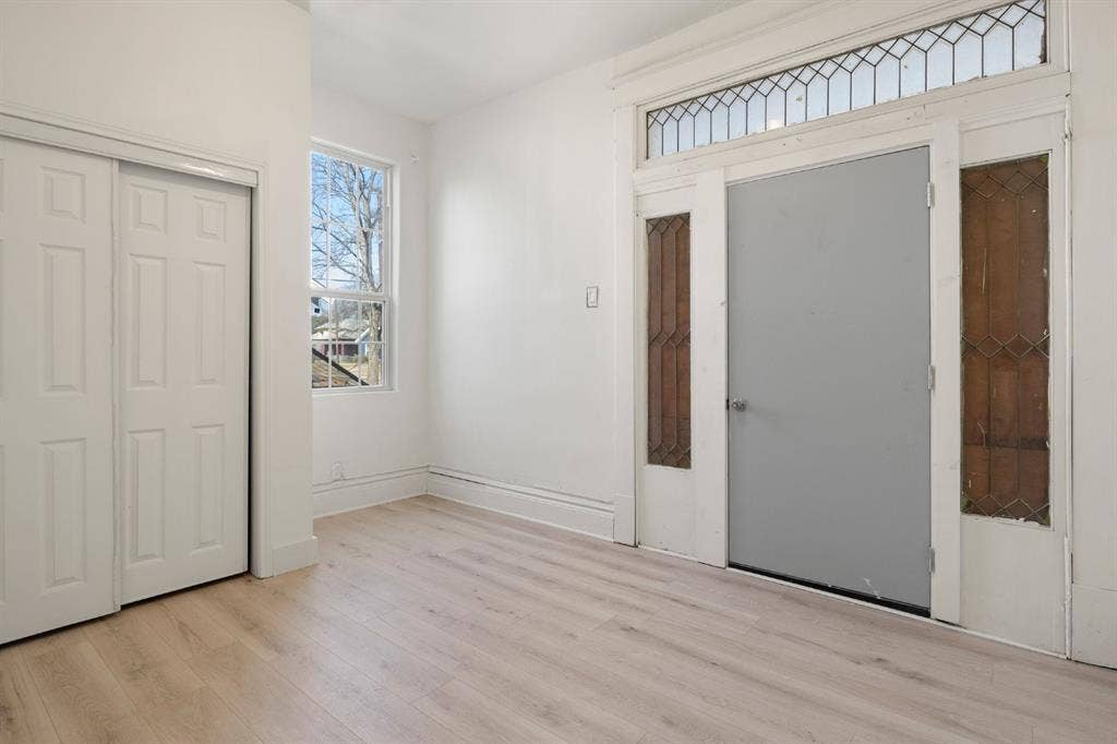 3711 Wendelkin Street, #1, Dallas, TX 75215 Interior space featuring wood-finish flooring, a multi-panel sliding closet, an exterior door with integrated leaded-glass sidelights, and a matching leaded-glass transom window