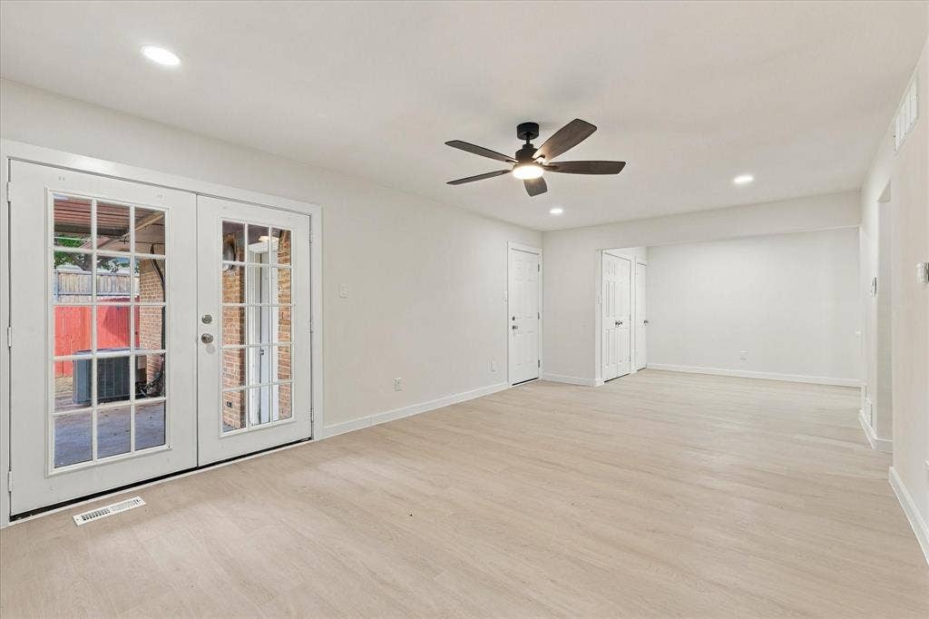 Interior featuring light-toned wood-finish flooring, recessed lighting, matte black ceiling fan, and white French doors with glass panes