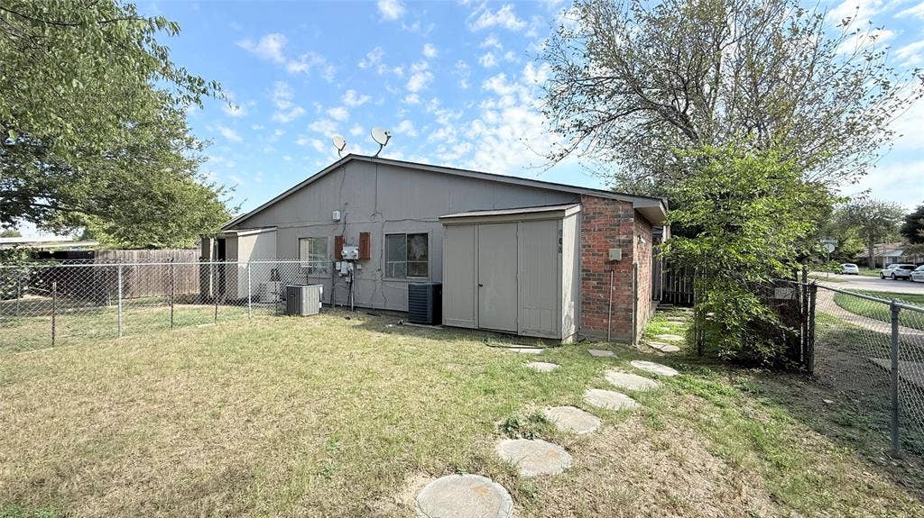 510 Matterhorn Street, Cedar Hill, TX 75104 Exterior featuring brick masonry, horizontal siding, attached storage shed, chain-link fencing, and stone paver walkway