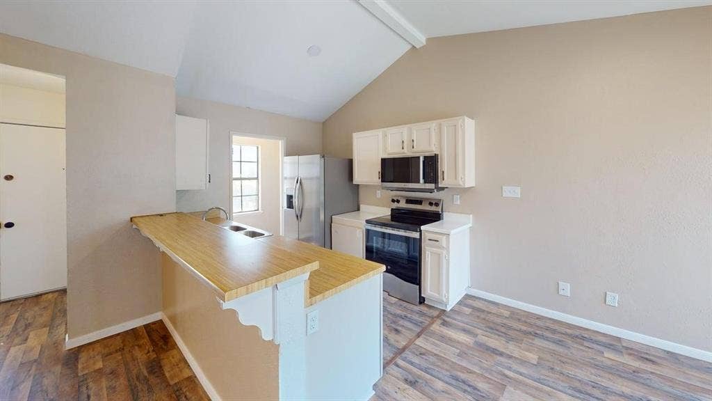 510 Matterhorn Street, Cedar Hill, TX 75104 Kitchen featuring white cabinetry, wood-finish countertop, stainless steel appliance package, and vaulted ceiling with wood-finish flooring