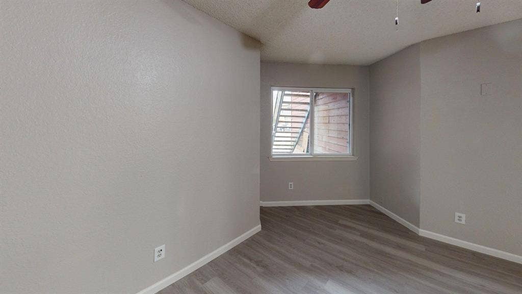 Interior space featuring neutral wall paint, wood-finish flooring, a sliding glass window, and an overhead ceiling fan