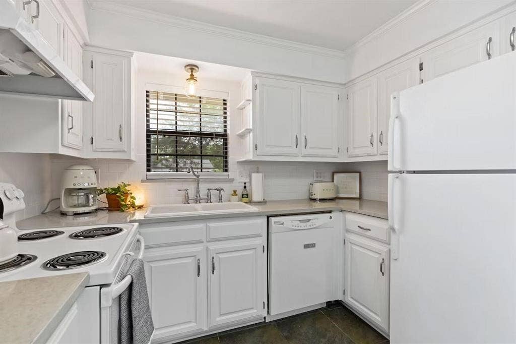 1101 N Waddill Street, McKinney, TX 75069 Kitchen featuring white cabinetry, solid surface countertops, a white double-basin sink with a gooseneck faucet, subway tile backsplash, and tile flooring