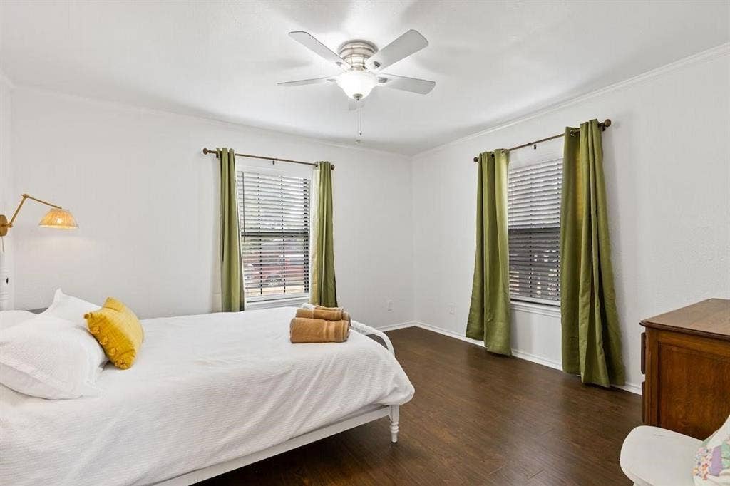 1101 N Waddill Street, McKinney, TX 75069 Room featuring dark wood-finish flooring, two dual-pane windows with horizontal blinds, a ceiling fan with integrated lighting, and a wall-mounted swing-arm light fixture