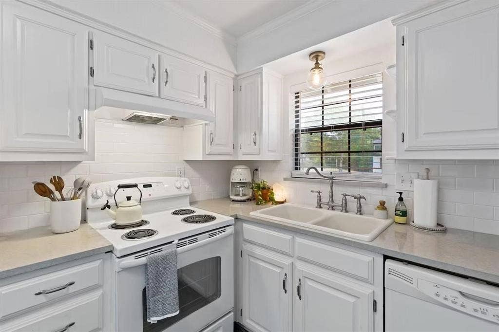 1101 N Waddill Street, McKinney, TX 75069 Kitchen featuring white cabinetry, subway tile backsplash, solid surface countertops, a dual-basin sink with a bridge-style faucet, and a range with an integrated hood