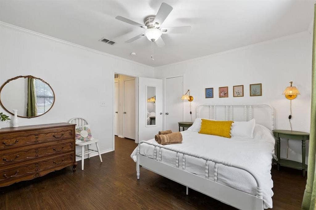 1101 N Waddill Street, McKinney, TX 75069 Bedroom interior featuring dark wood-finish flooring, a white ceiling fan with integrated lighting, and dual wall-mounted brass sconces