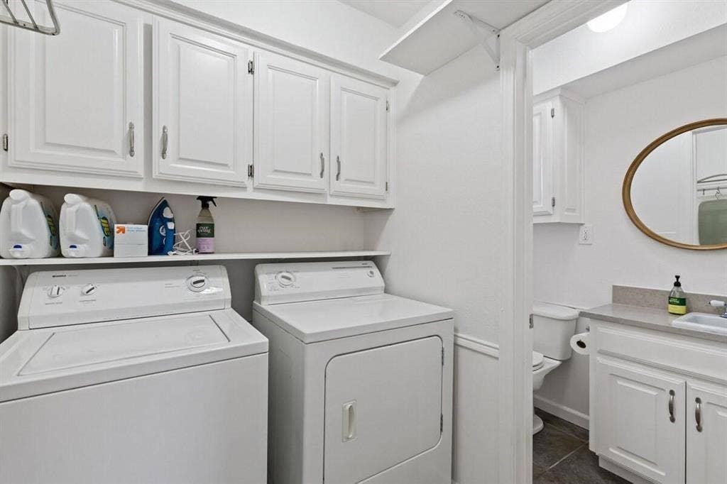 1101 N Waddill Street, McKinney, TX 75069 Laundry area featuring white shaker-style cabinetry, open shelving, and a stone-surface vanity with an integrated sink