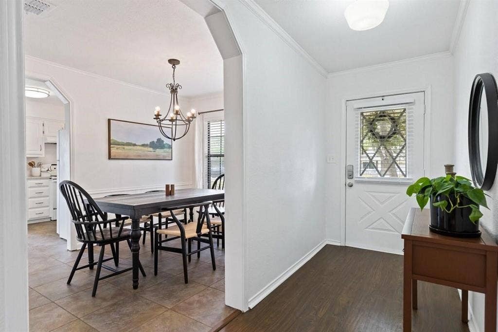 1101 N Waddill Street, McKinney, TX 75069 Entryway featuring dark wood-finish flooring, an arched threshold, a white exterior door with glass insert, ceramic tile flooring, and a decorative hanging chandelier