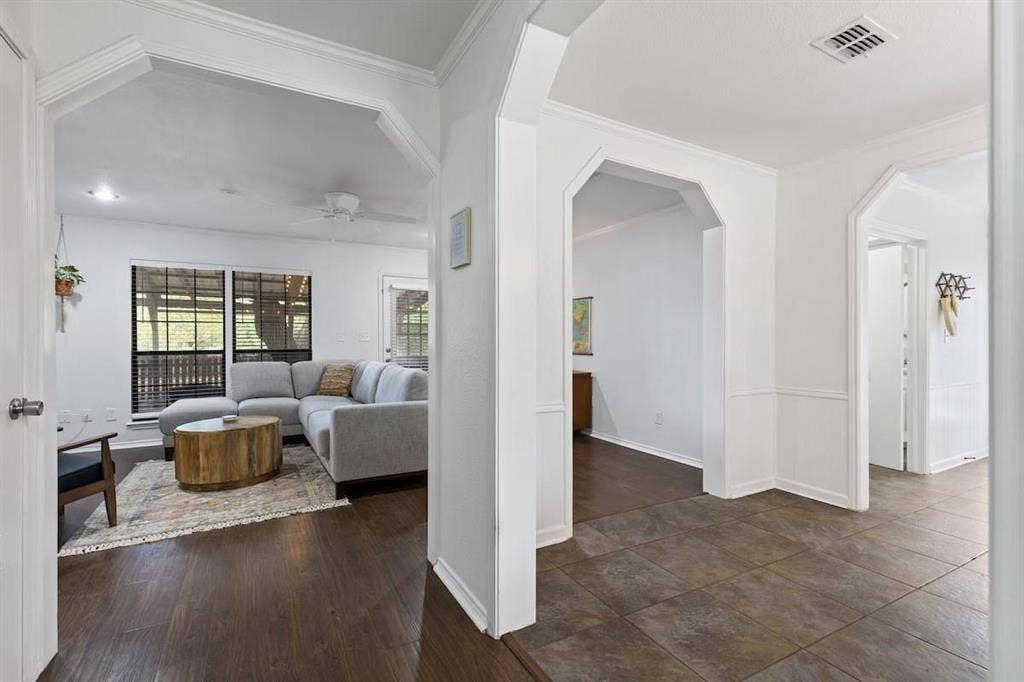 1101 N Waddill Street, McKinney, TX 75069 Interior featuring large architectural archways, dark wood-finish flooring, and earth-tone tile flooring with wainscoting