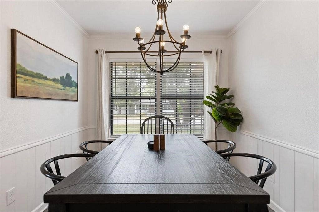 1101 N Waddill Street, McKinney, TX 75069 Dining area featuring vertical wainscoting, crown molding, and a central iron chandelier