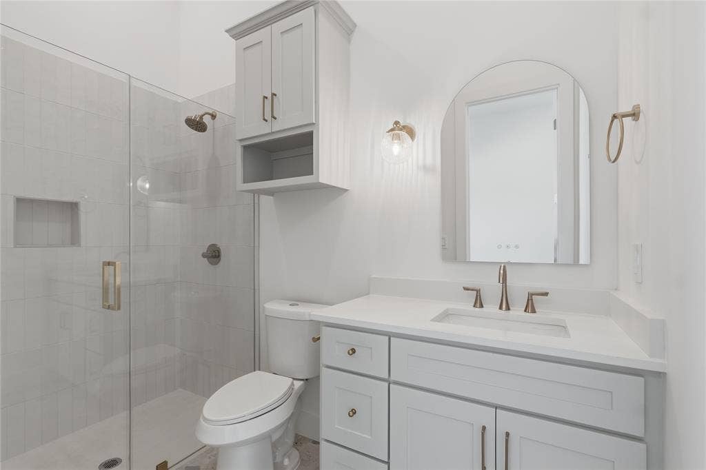 Bathroom featuring a glass-enclosed shower with tile surround, a built-in shower niche, and brushed nickel fixtures