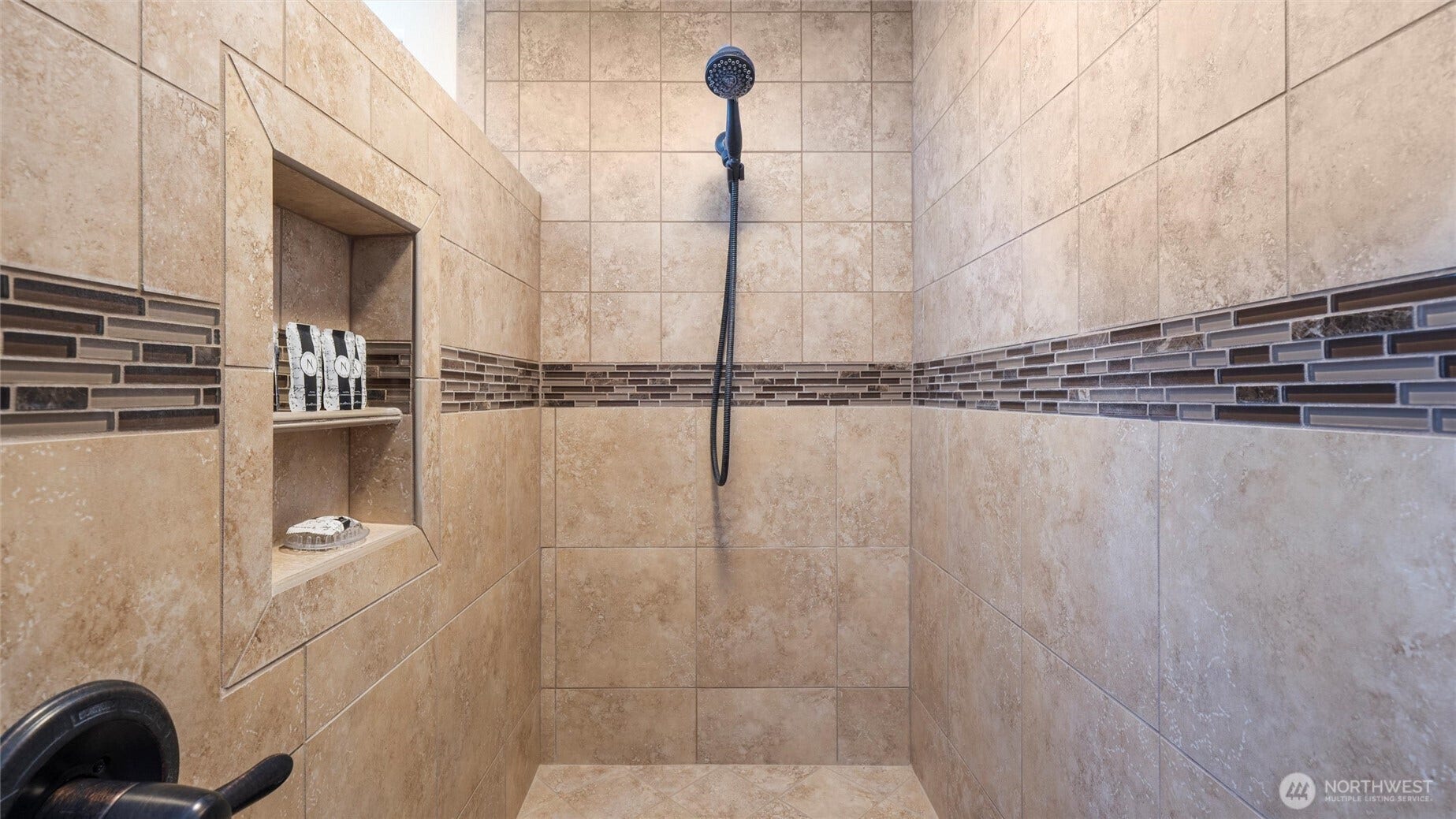 Oversized step-in shower with shower bench and recessed nook for all your bathing accessories.