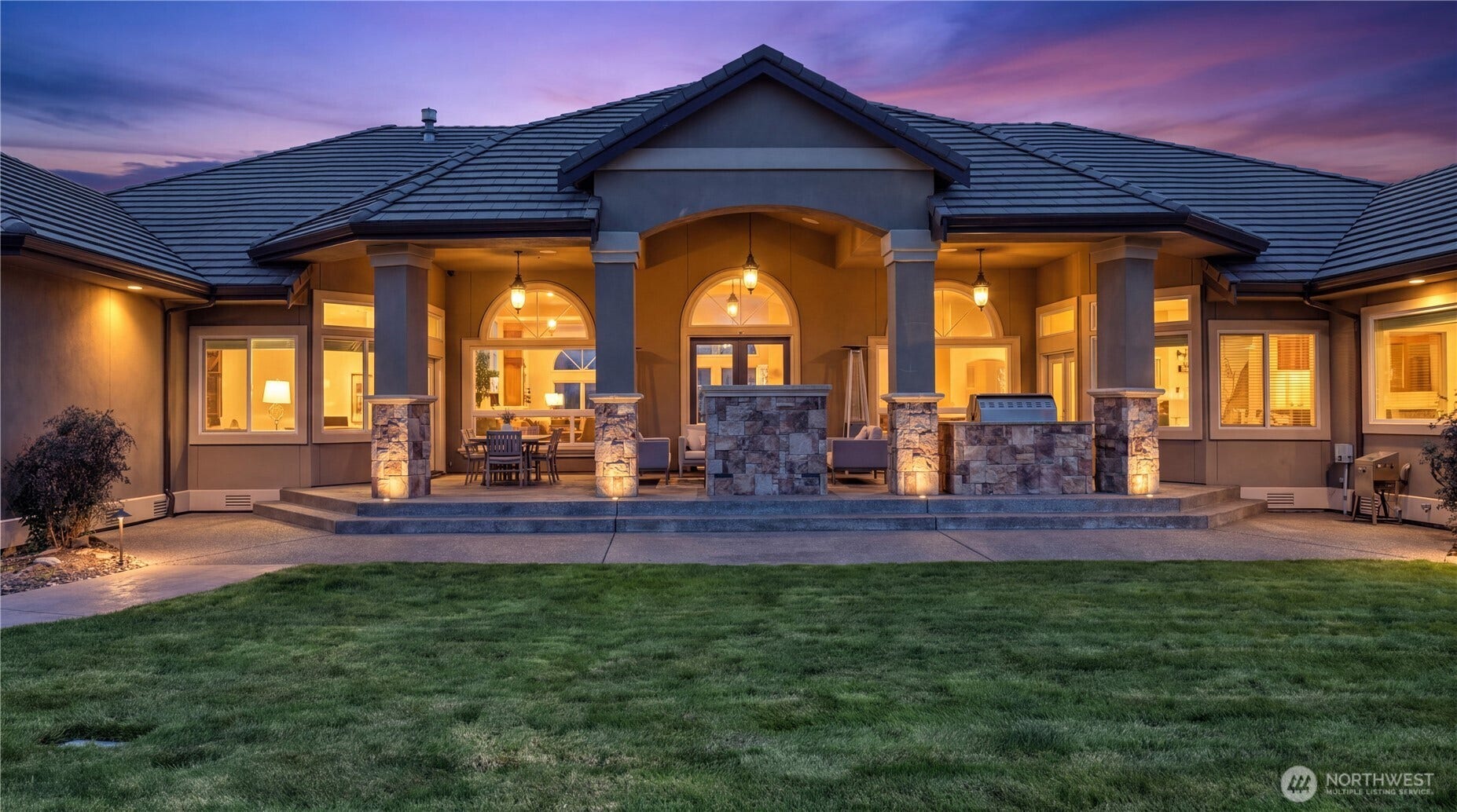 Backyard Patio & Outdoor Kitchen    The inviting backyard patio offers a seamless blend of elegance and functionality, perfect for entertaining or relaxing at sunset. Under the covered arches, warm lighting highlights the spacious seating and dining areas, while the built-in outdoor kitchen and BBQ grill make alfresco gatherings effortless. Framed by stone accents and surrounded by manicured lawn, this space captures the essence of refined outdoor living.