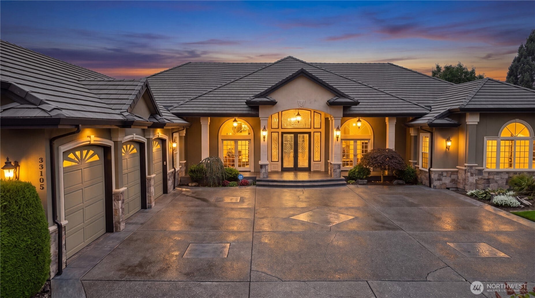 Front Exterior    This stunning front exterior showcases timeless elegance and curb appeal. The home features a grand covered entry framed by stately columns, arched windows, and warm evening lighting that highlights its architectural details. A spacious circular driveway leads to a three-car garage with ample storage, offering both convenience and sophistication. The beautifully landscaped approach and refined faade create a welcoming first impression that perfectly complements the homes luxury design.