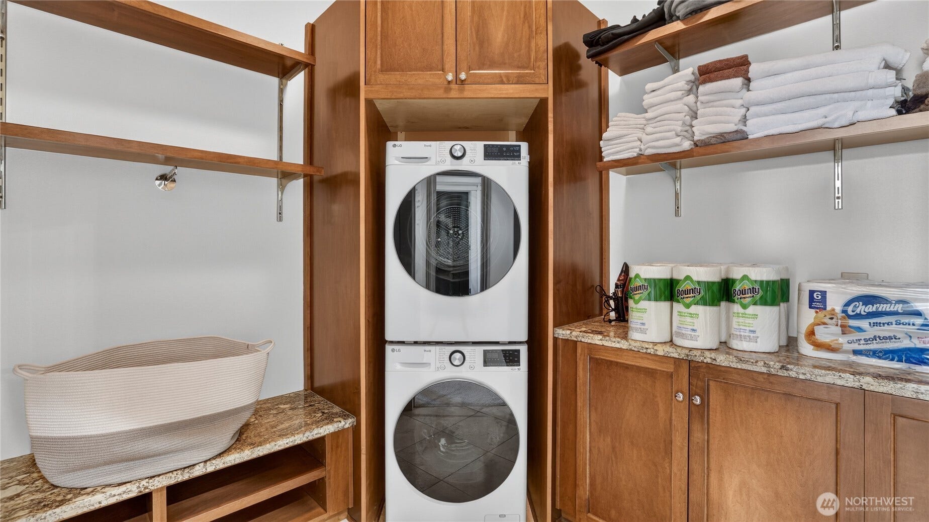 Laundry in Primary Suite    Conveniently located within the primary suite, this beautifully designed laundry area features a stacked washer and dryer, custom cabinetry, and granite countertops for folding and organization. Open shelving provides ample space for linens and essentials, creating a clean, efficient, and stylish setup that enhances everyday living.