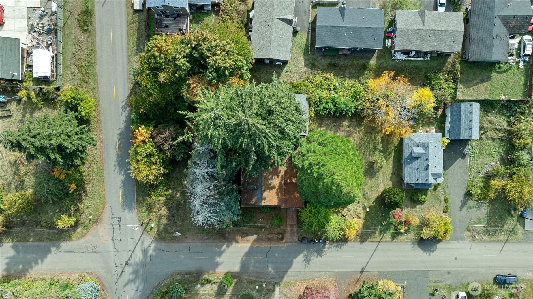corner lot with trees, house in middle and mostly cleared lot to the right of the house.