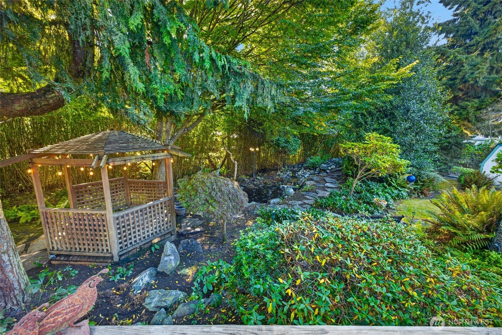 The gazebo overlooks a pond receiving water from a gentle river with waterfall.
