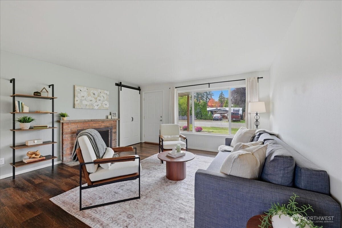 20807 3rd Avenue W, Lynnwood, WA 98036 Warm and welcoming living room with classic brick wood burning fireplace, beautiful luxury vinyl plank flooring and abundant natural light