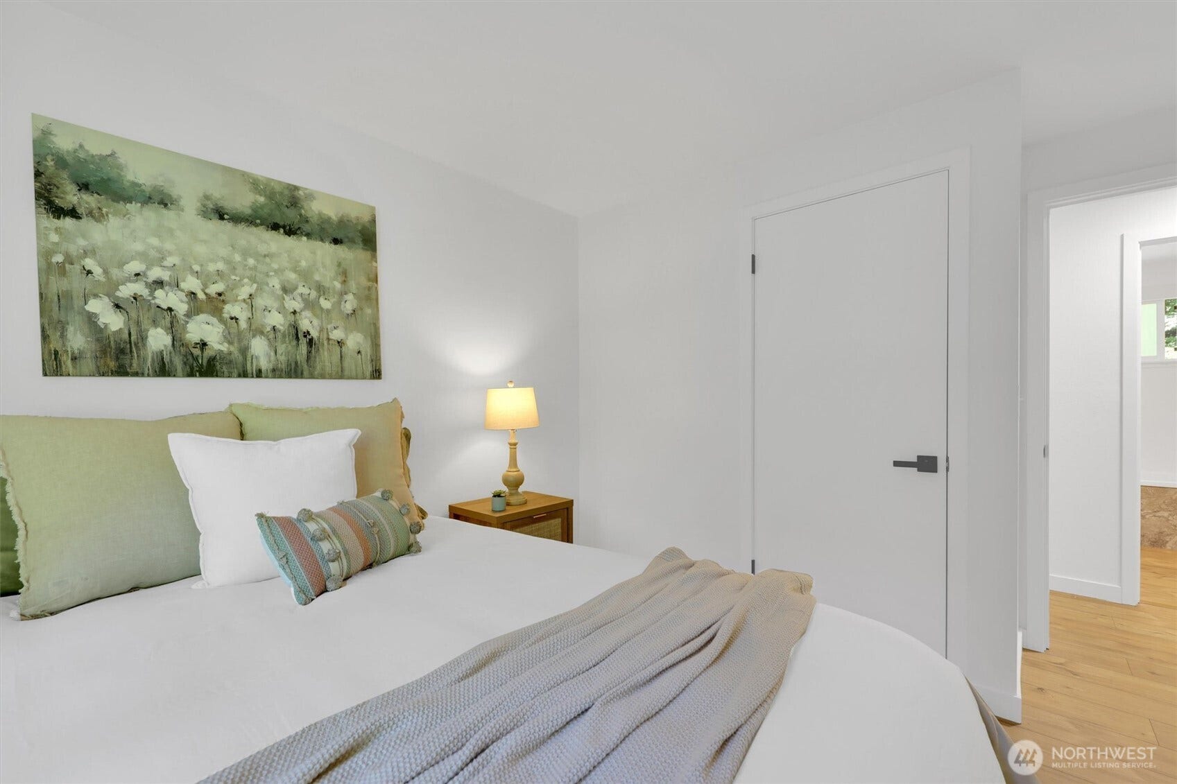 20915 W Richmond Road, Bothell, WA 98021 Bright bedroom featuring a bed, nightstand, table lamp, hardwood flooring, closet door, and soft neutral dcor.