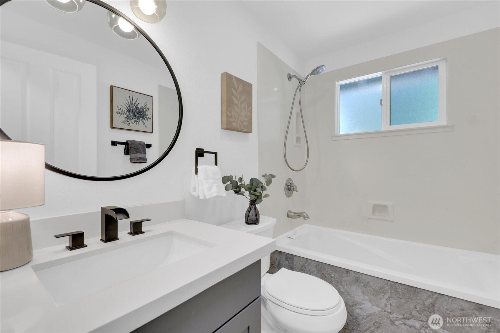 20915 W Richmond Road, Bothell, WA 98021 Bright full bathroom with modern vanity, round mirror, bathtub, gray tile surround, contemporary fixtures, and natural light.