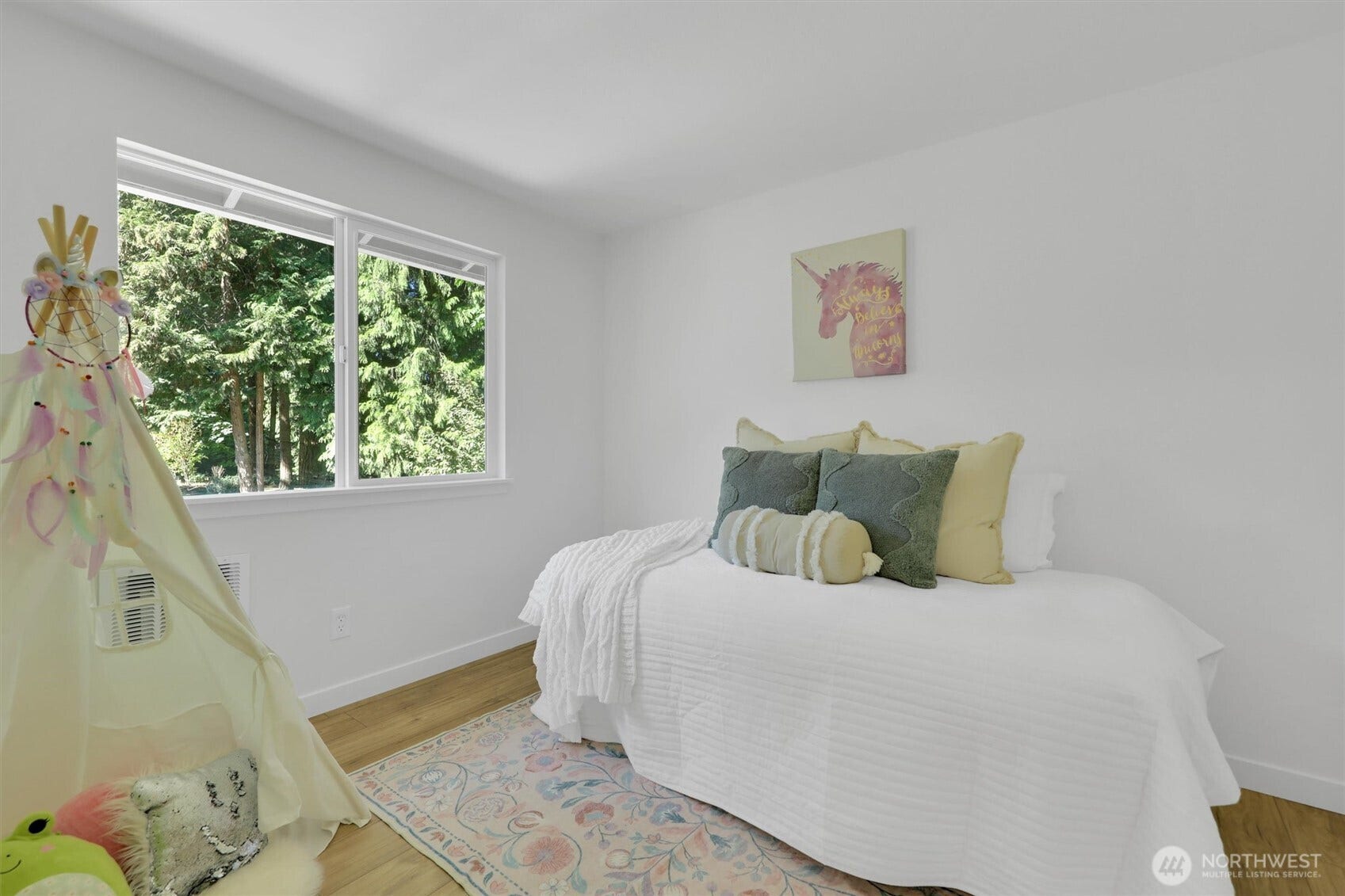 20915 W Richmond Road, Bothell, WA 98021 Sunny bedroom with a neatly made bed, large window, hardwood flooring, colorful area rug, and soft neutral furnishings.