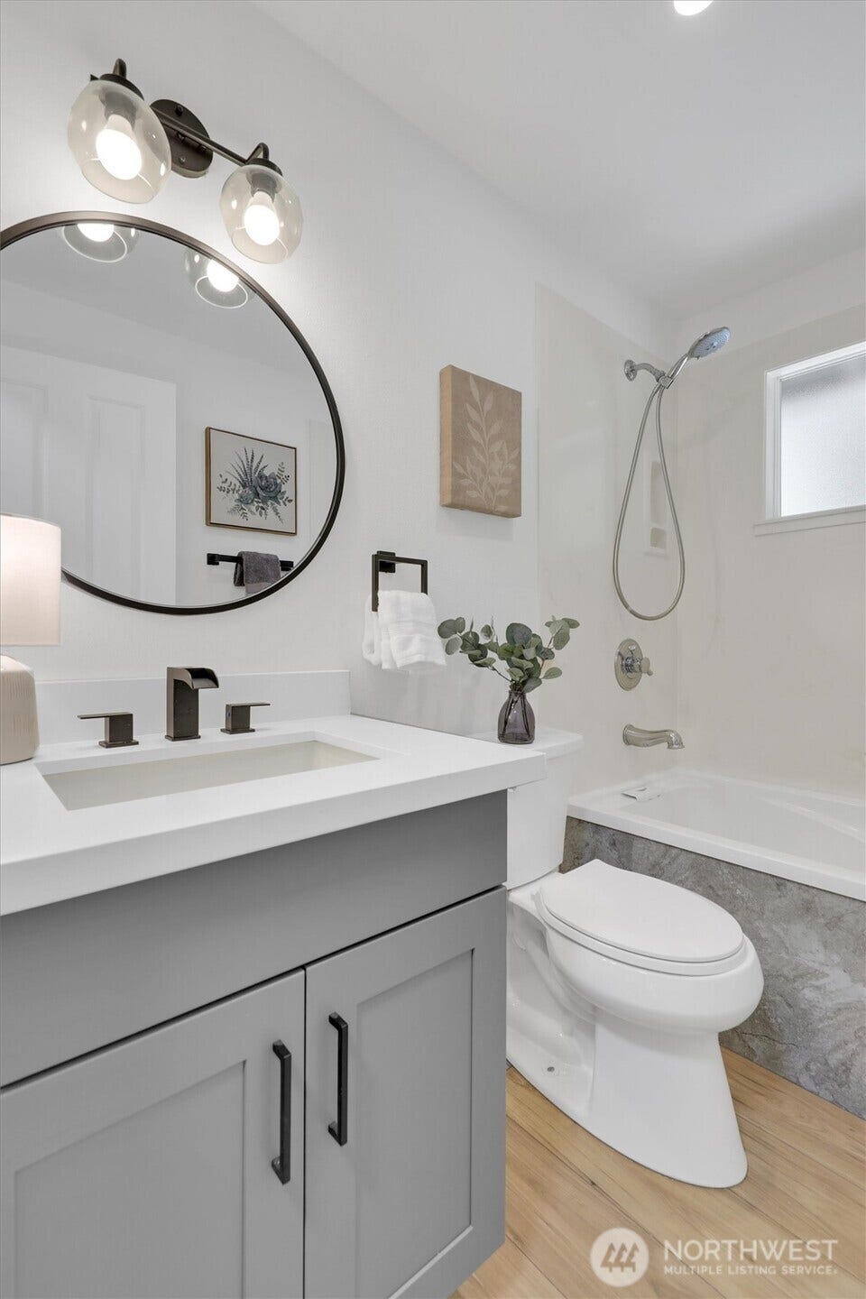 20915 W Richmond Road, Bothell, WA 98021 Updated bathroom featuring a modern vanity, round mirror, white fixtures, contemporary lighting, and a clean neutral design.
