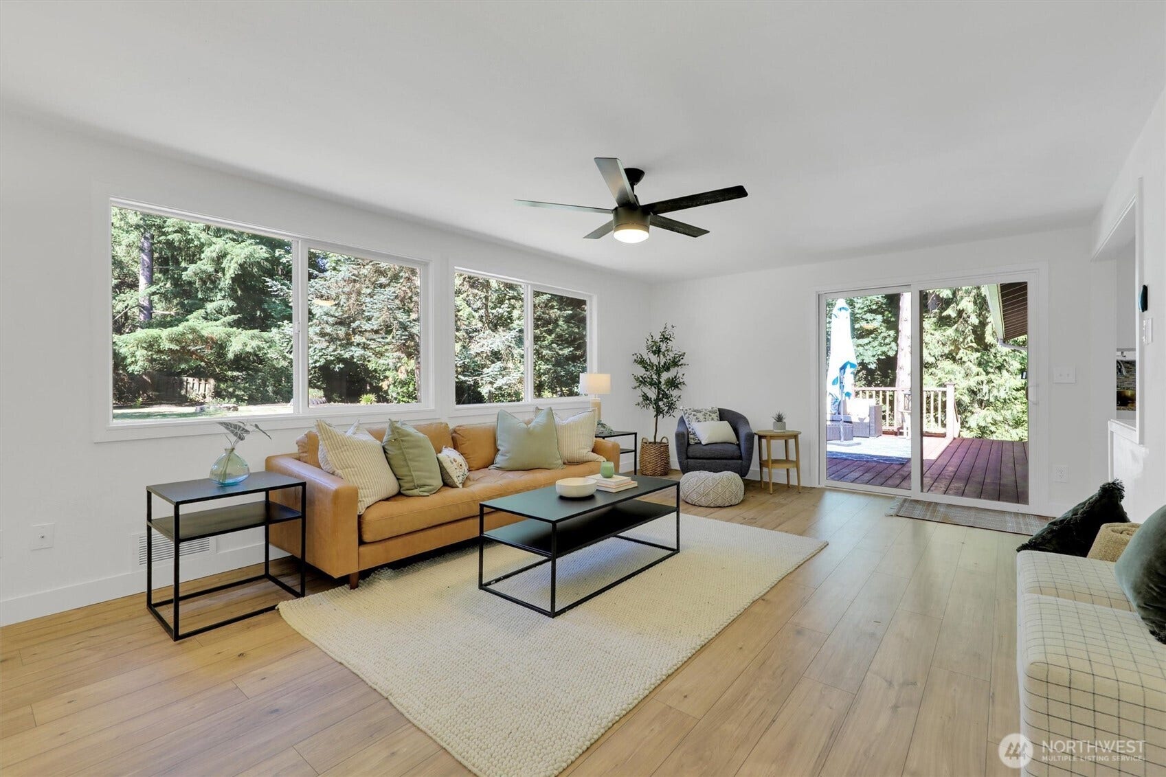 20915 W Richmond Road, Bothell, WA 98021 Open living area featuring hardwood floors, large windows, ceiling fan, seating area, and glass door leading toward the outdoor space.