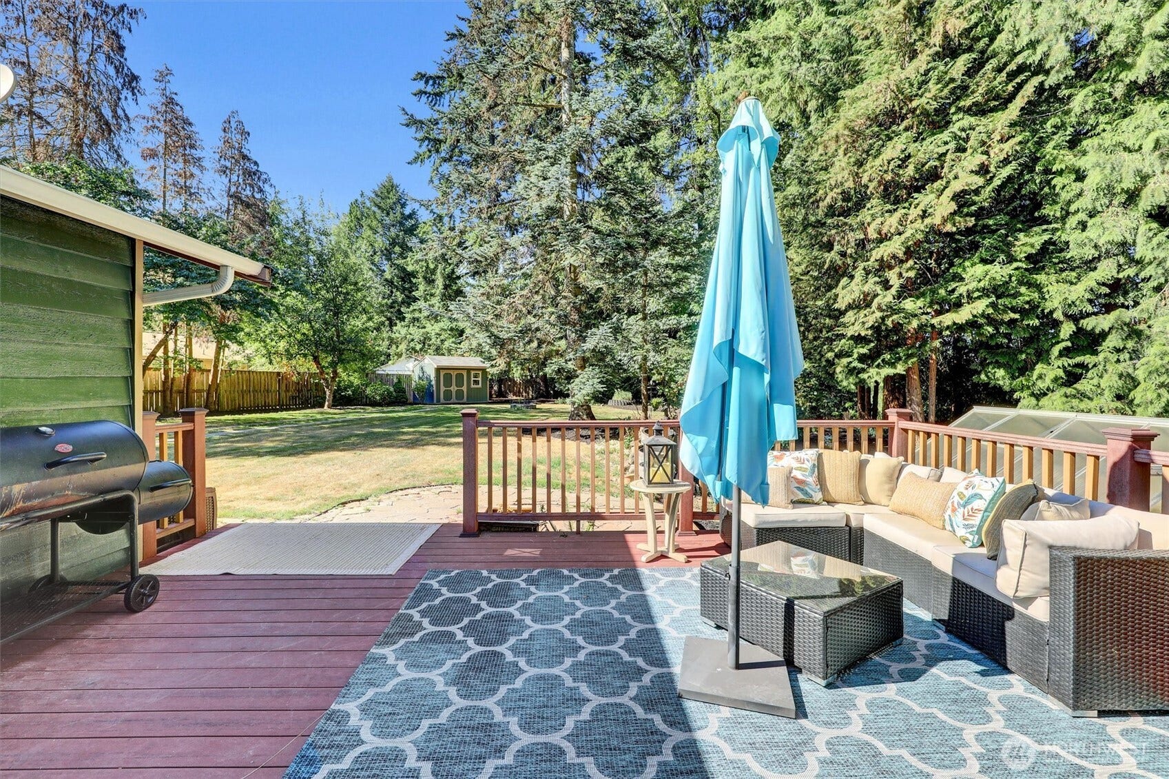 20915 W Richmond Road, Bothell, WA 98021 Large outdoor entertaining deck with seating area, umbrella, grill, and views of the private tree-lined yard.