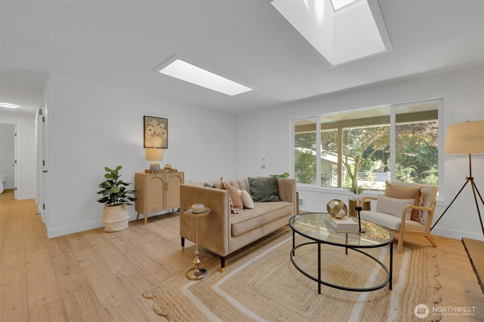 20915 W Richmond Road, Bothell, WA 98021 Bright living area with hardwood floors, skylights, comfortable seating, and large windows providing views of the surrounding trees.