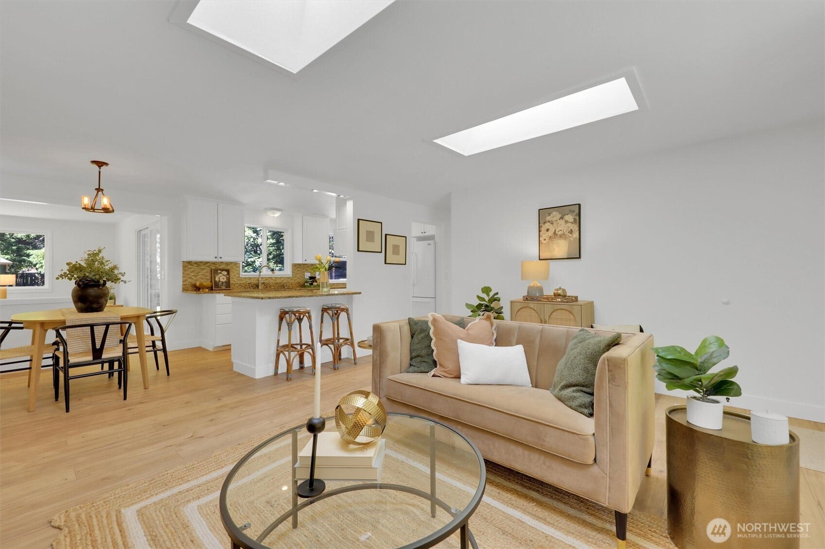 20915 W Richmond Road, Bothell, WA 98021 Bright open-concept living room and dining area featuring hardwood floors, skylights, comfortable seating, and large windows overlooking the greenery.