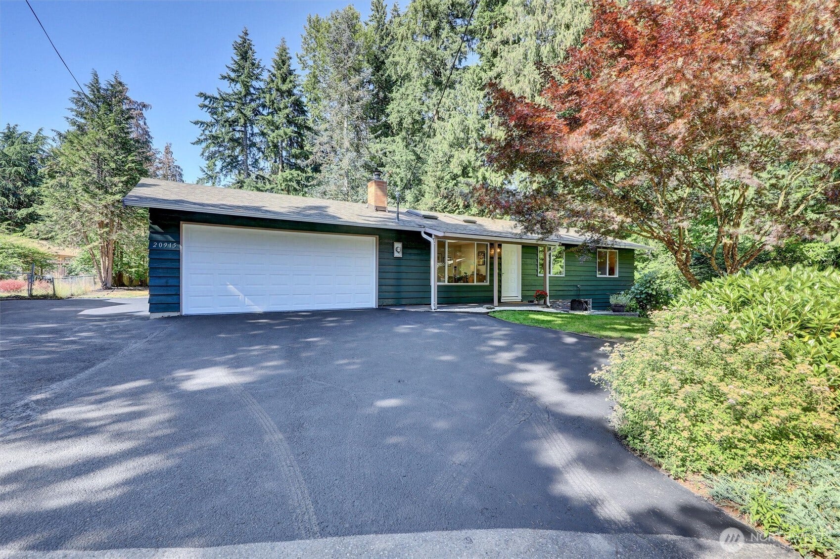 20915 W Richmond Road, Bothell, WA 98021 Front exterior view of the Bothell home featuring the attached two-car garage, large driveway, mature landscaping, and surrounding trees.